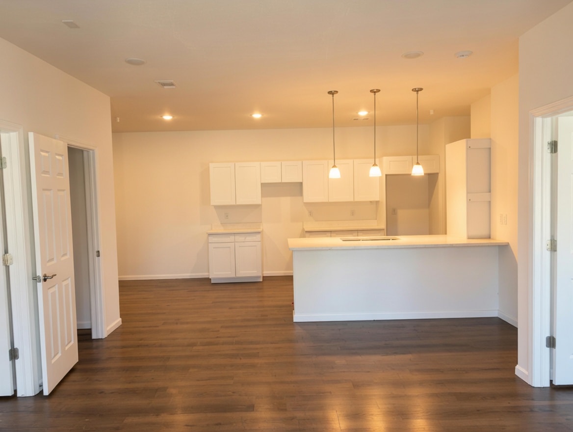 A kitchen with white cabinets and a wooden floor.